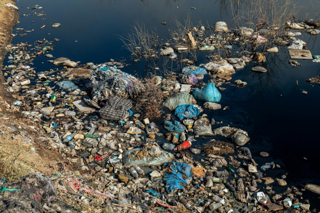 An aerial shot of a polluted riverbank covered with plastic waste and debris highlighting environmental issues.